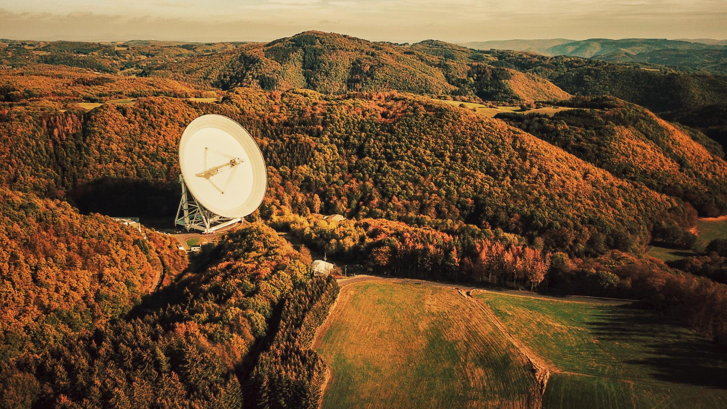 Large ground satellite dish in a rural landscape linked to methane detection satelites for tracking methane emissions across wide areas.